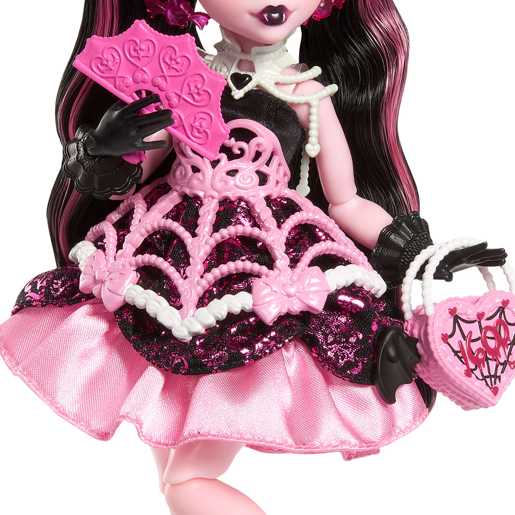 Parti elbisesi giyen ve bir elinde balon, diğer elinde hediyesini tutan Monster High Doğum Günü Draculaura bebek