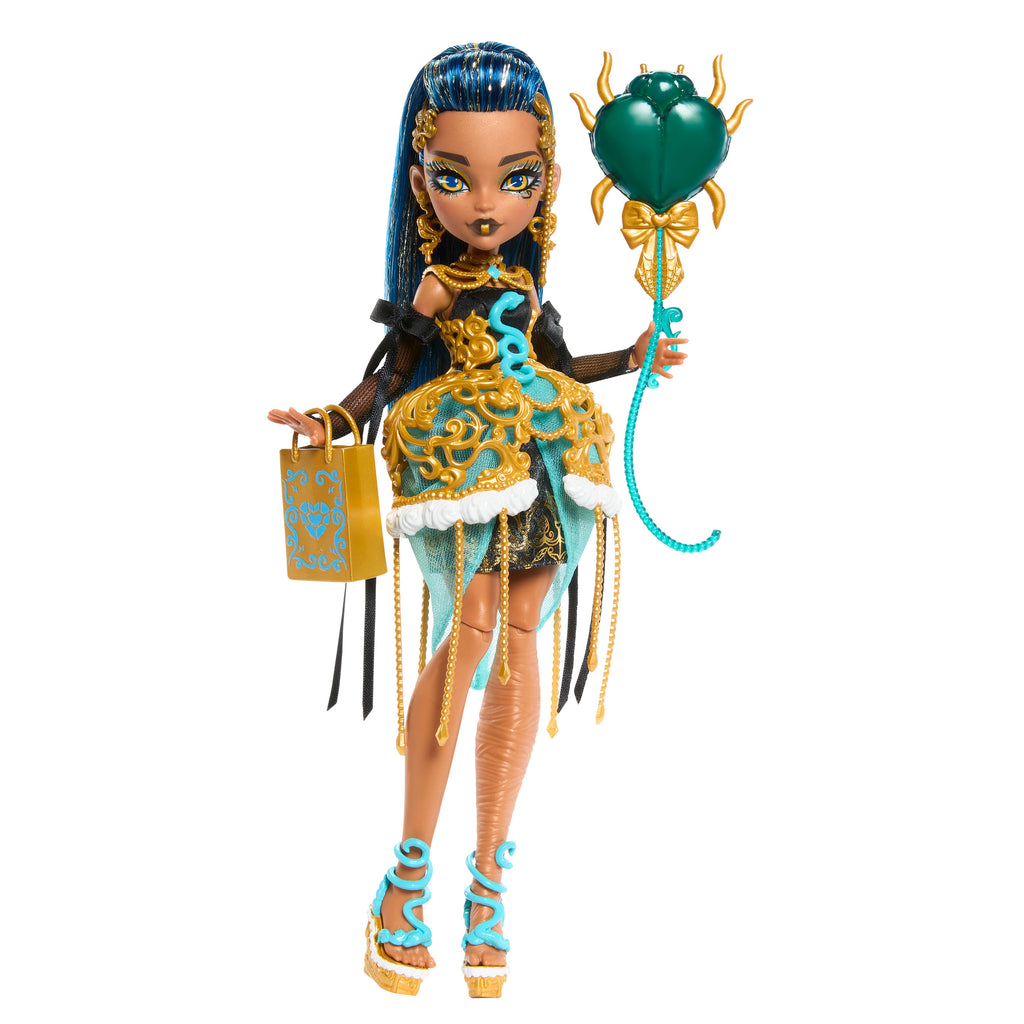 Parti elbisesi giyen ve bir elinde balon, diğer elinde hediyesini tutan Monster High Doğum Günü Cleo De Nile bebek